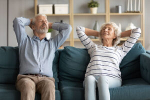 A couple relaxing on a couch and taking a deep breath.