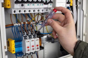 Hickey technician using screwdriver to fix electrical panel.