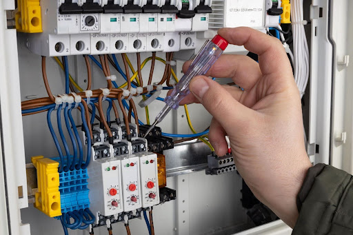 Hickey technician using screwdriver to fix electrical panel.
