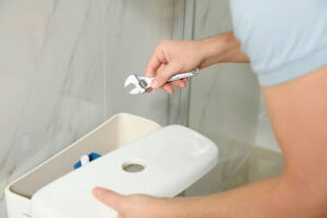 Homeowner removing toilet tank lid to fix plumbing problem.