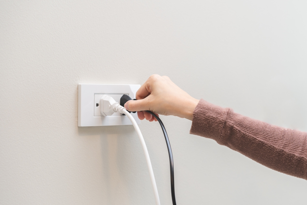 a woman's hand putting a plugging into an electrical outlet