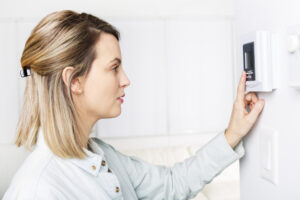 woman adjusting the thermostat